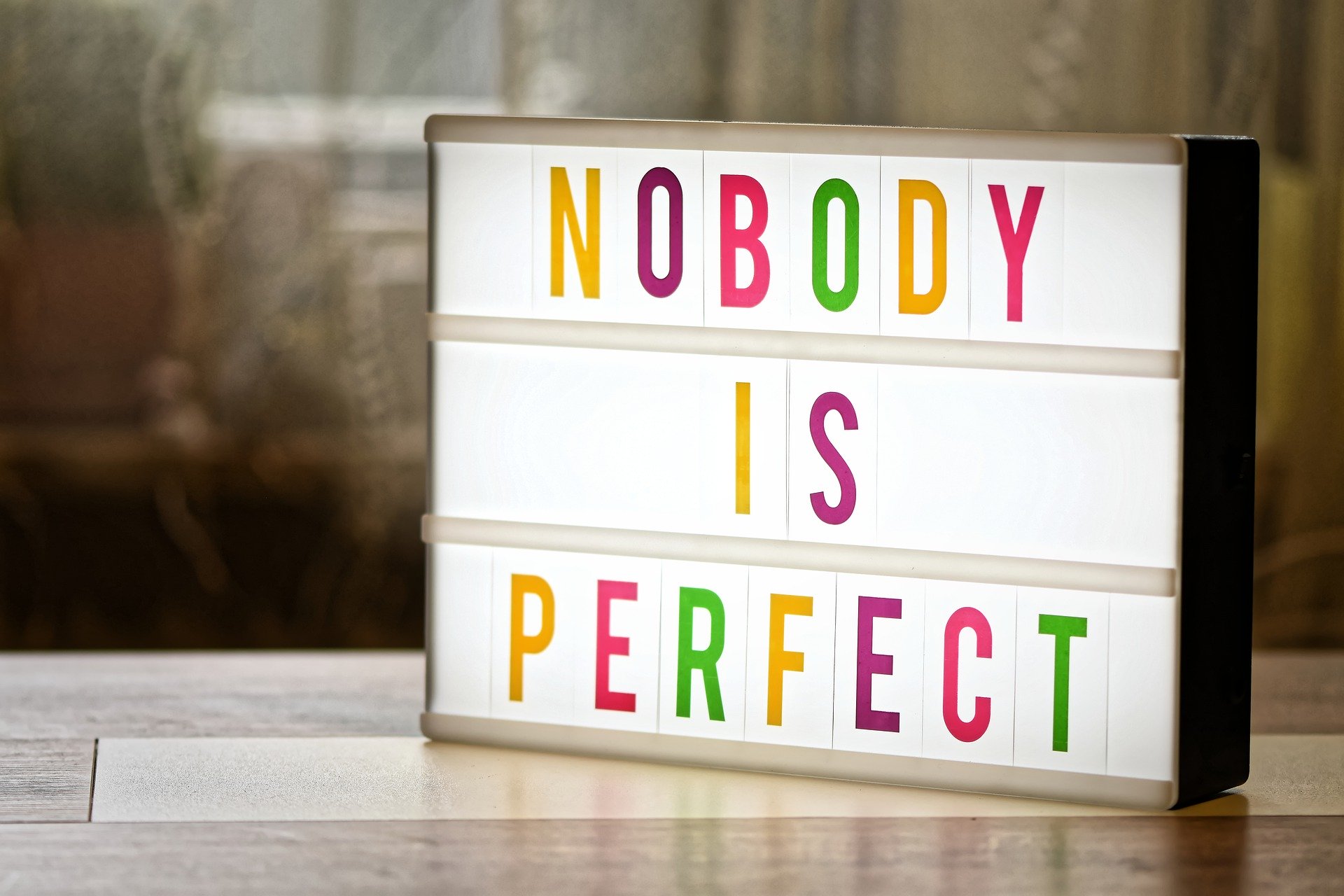 Auf einem Tisch ein Schild mit Aufschrift "NOBODY IS PERFECT".